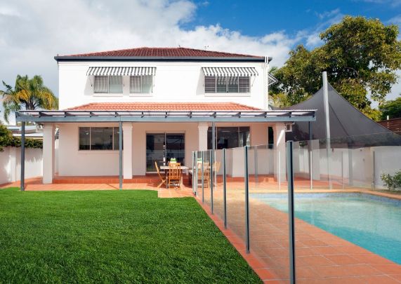 backyard with a lawn and a pool separated by glass fence | Werribee Fencing Pros